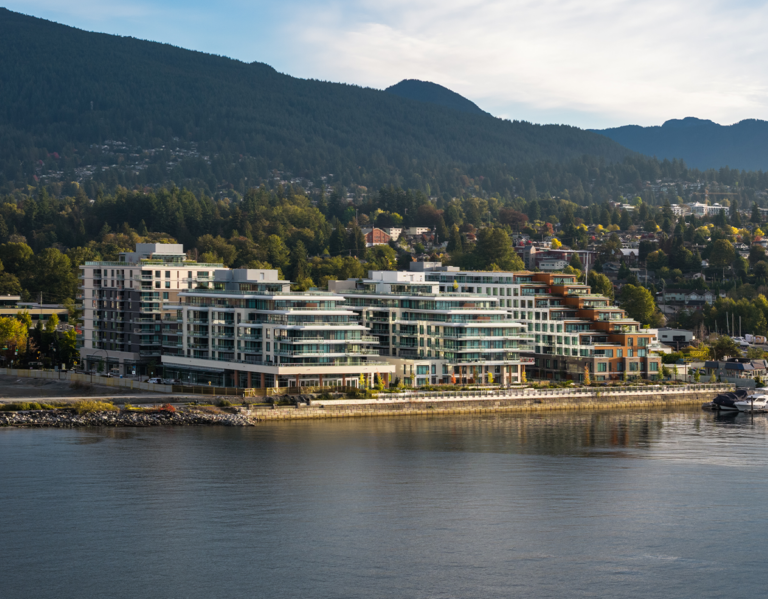 The four buildings of Phase 1 with the North Shore mountains in the background and the waterfront in front on a beautiful day.